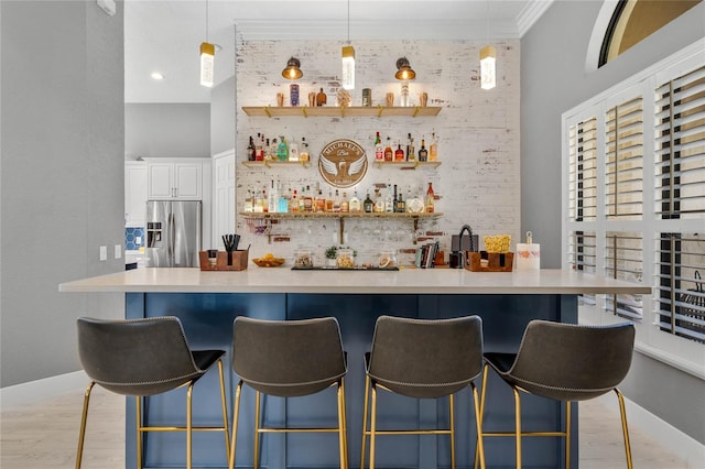 bar featuring stainless steel fridge, brick wall, a high ceiling, white cabinetry, and hanging light fixtures