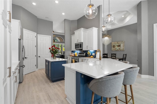 kitchen with pendant lighting, a high ceiling, blue cabinetry, a kitchen island, and stainless steel appliances