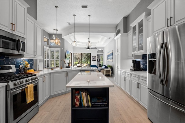 kitchen featuring white cabinets, backsplash, a kitchen island, and stainless steel appliances