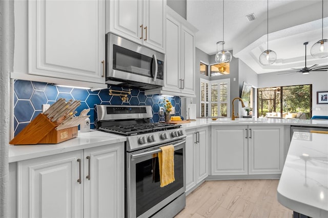 kitchen with tasteful backsplash, a textured ceiling, stainless steel appliances, white cabinetry, and hanging light fixtures