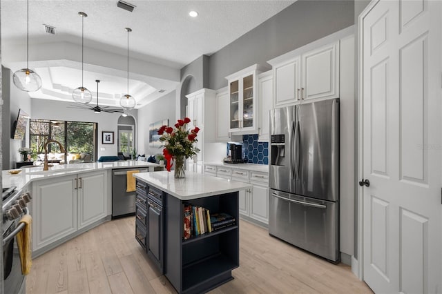 kitchen with stainless steel appliances, sink, decorative light fixtures, white cabinets, and a center island