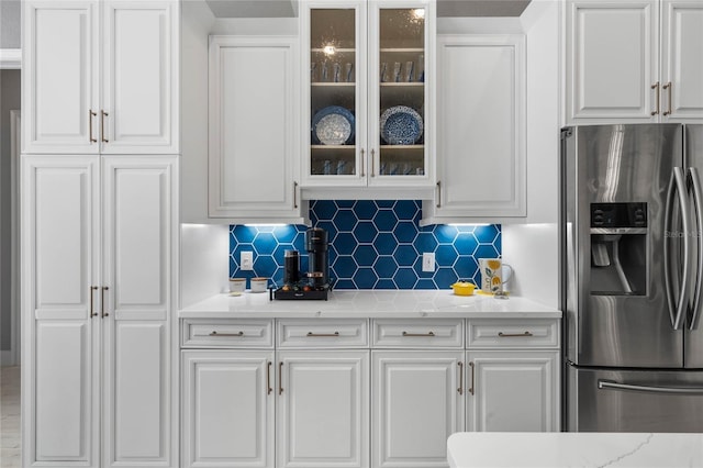 kitchen with white cabinetry, light stone countertops, stainless steel fridge with ice dispenser, and tasteful backsplash