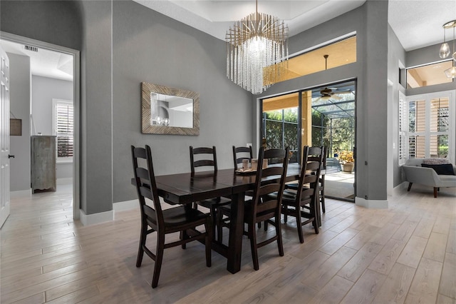 dining room with hardwood / wood-style floors, a notable chandelier, a healthy amount of sunlight, and a high ceiling