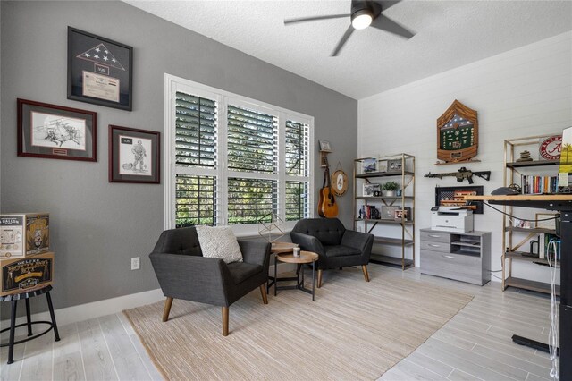 living room with ceiling fan, light hardwood / wood-style flooring, and a textured ceiling