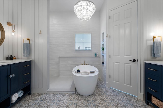 bathroom with tile patterned flooring, a notable chandelier, a washtub, and vanity