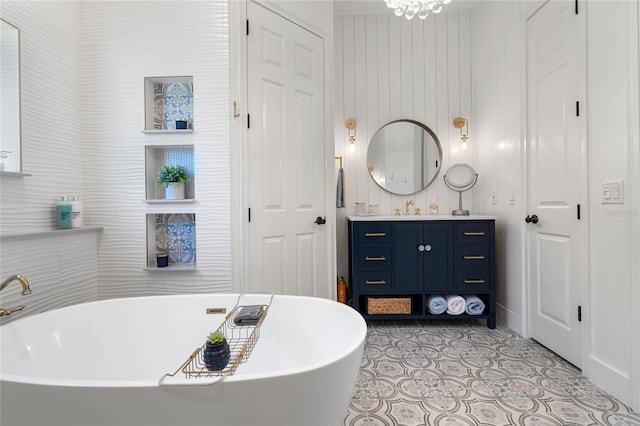 bathroom featuring tile patterned flooring, vanity, a tub, and a notable chandelier