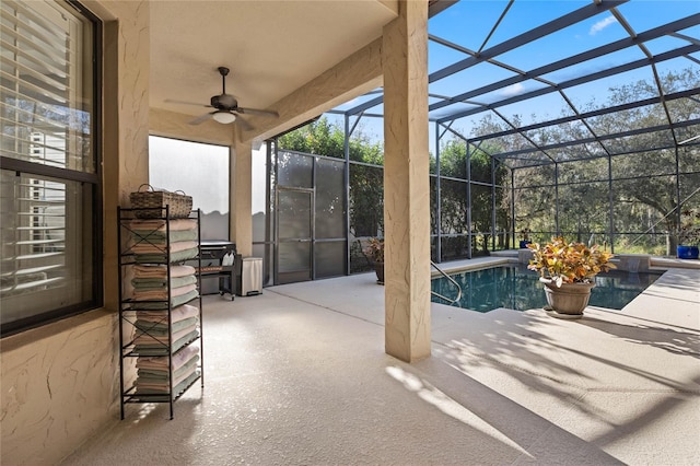 view of pool featuring a patio, glass enclosure, and ceiling fan