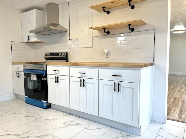 kitchen featuring butcher block counters, white cabinetry, wall chimney range hood, tasteful backsplash, and range with electric stovetop