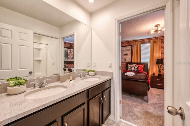 bathroom featuring vanity, a textured ceiling, and brick wall