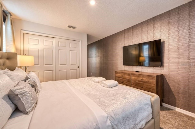 carpeted bedroom featuring a textured ceiling and a closet