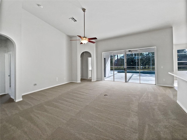 unfurnished living room featuring ceiling fan, a towering ceiling, and carpet