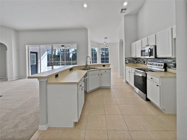 kitchen featuring appliances with stainless steel finishes, backsplash, sink, light tile patterned floors, and white cabinets