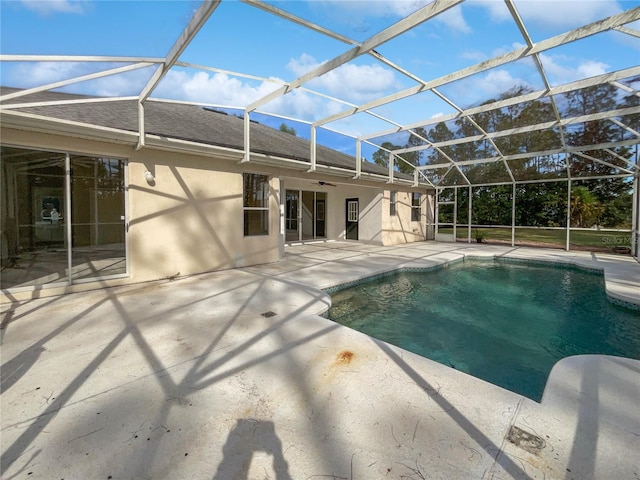 view of swimming pool featuring glass enclosure, ceiling fan, and a patio area