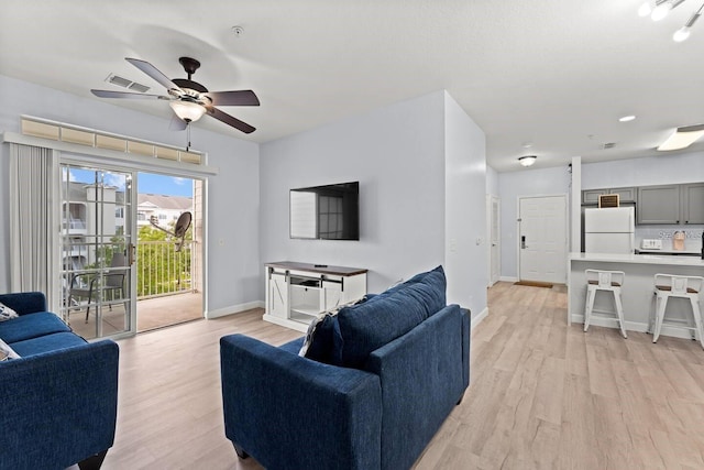 living room with light hardwood / wood-style floors and ceiling fan