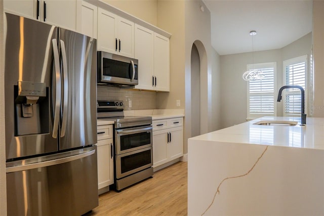 kitchen featuring light stone counters, stainless steel appliances, white cabinetry, and sink