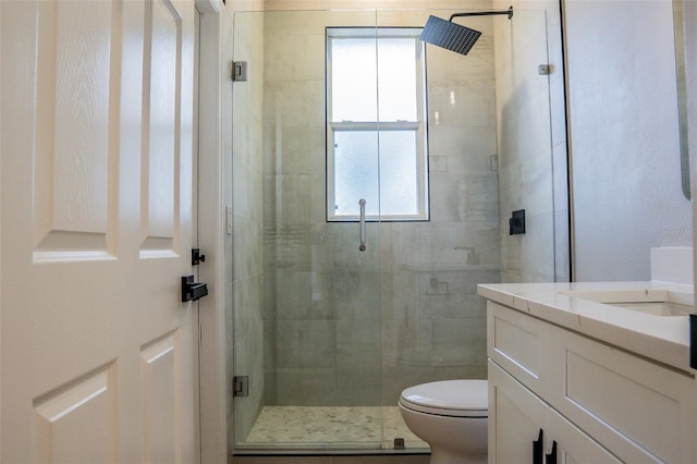 bathroom with vanity, a shower with shower door, and toilet