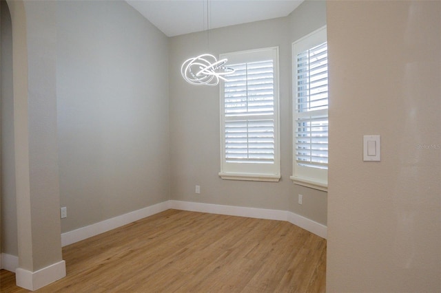 empty room featuring light hardwood / wood-style flooring and an inviting chandelier