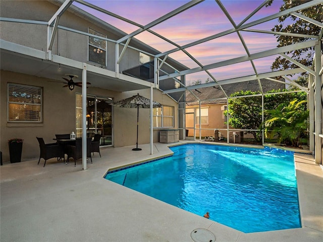 pool at dusk with a lanai, ceiling fan, and a patio