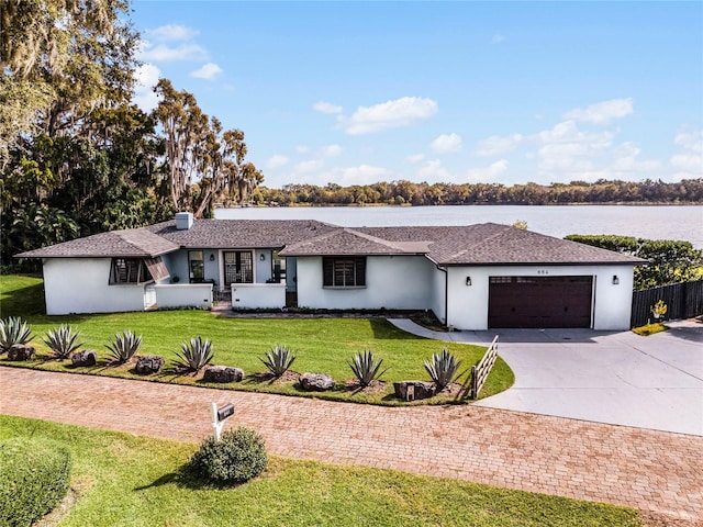 ranch-style home featuring a front lawn, a garage, and a water view