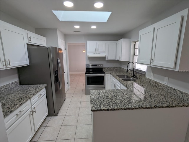 kitchen with sink, a skylight, dark stone countertops, white cabinetry, and stainless steel appliances