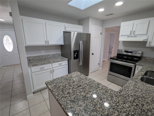 kitchen with a skylight, white cabinets, light tile patterned flooring, and appliances with stainless steel finishes