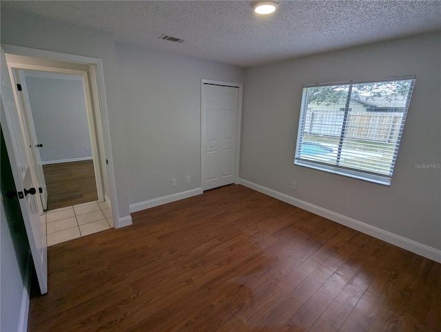 unfurnished bedroom featuring a closet, a textured ceiling, and hardwood / wood-style flooring