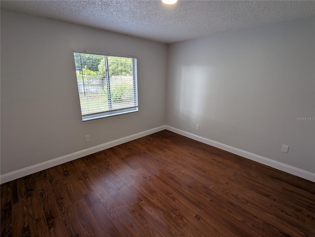 spare room featuring dark hardwood / wood-style flooring and a textured ceiling