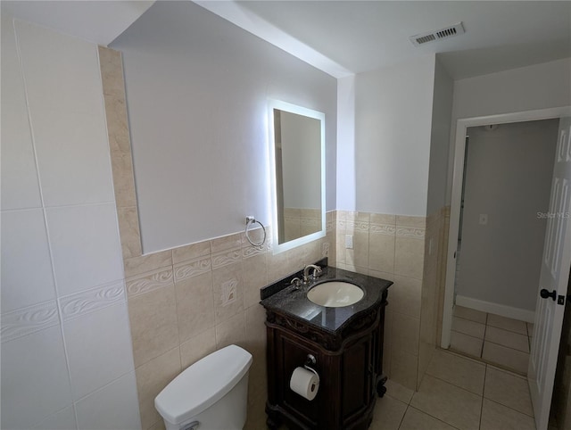 bathroom featuring tile patterned flooring, vanity, toilet, and tile walls