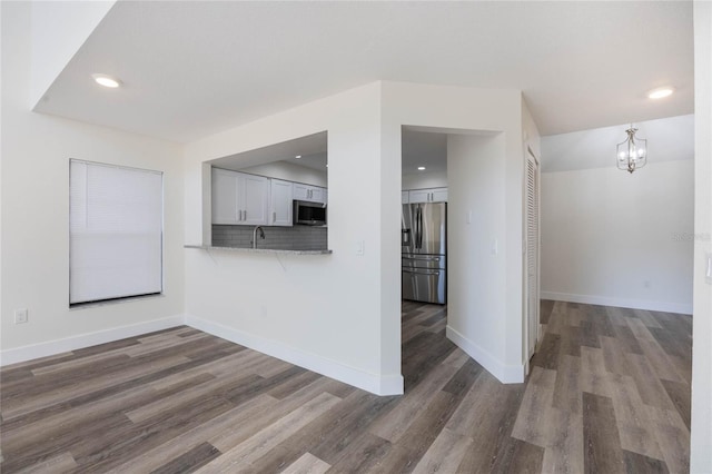 unfurnished living room with dark wood-type flooring and a chandelier