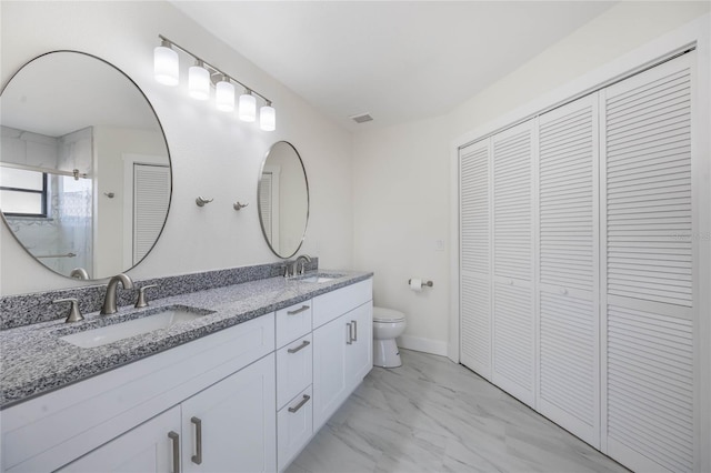 bathroom featuring vanity, a shower with shower door, and toilet