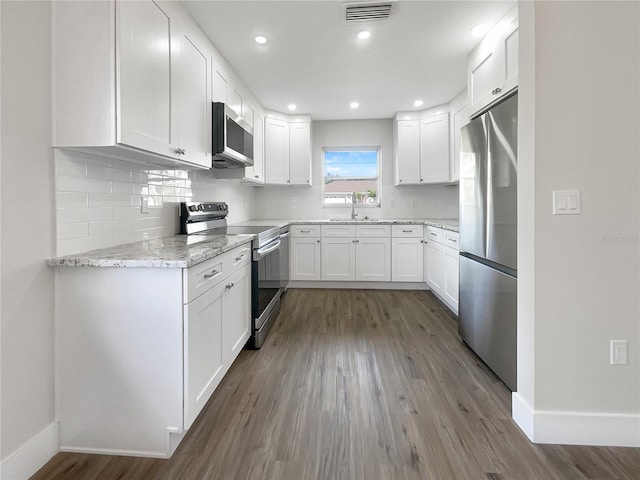 kitchen with light stone countertops, sink, stainless steel appliances, dark hardwood / wood-style flooring, and white cabinets