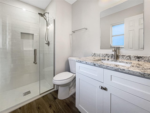 bathroom featuring hardwood / wood-style flooring, vanity, toilet, and walk in shower