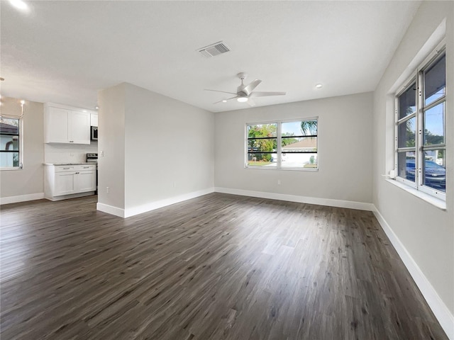 unfurnished living room featuring ceiling fan with notable chandelier and dark hardwood / wood-style flooring