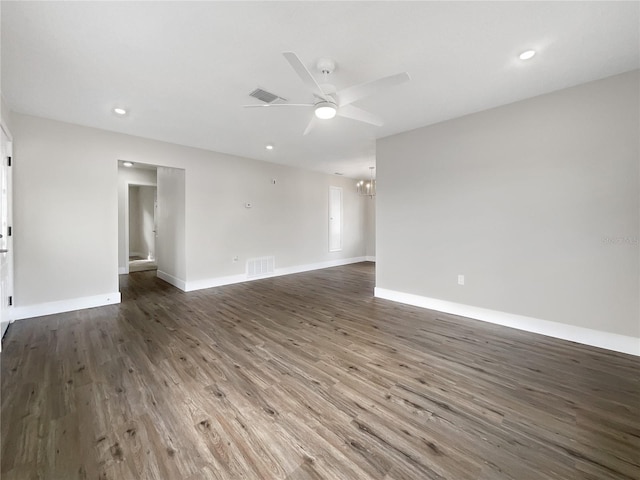 spare room featuring ceiling fan with notable chandelier and dark hardwood / wood-style flooring