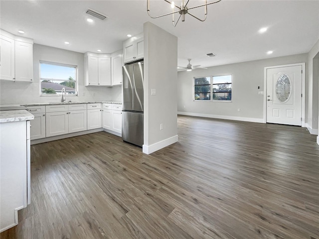 kitchen with decorative backsplash, stainless steel fridge, white cabinetry, and sink