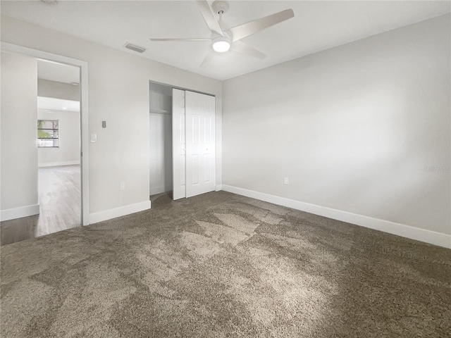 unfurnished bedroom with dark colored carpet, a closet, and ceiling fan