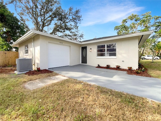 ranch-style home featuring cooling unit, a garage, and a front lawn