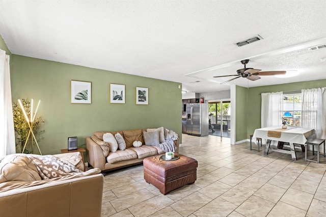 living room featuring ceiling fan and a textured ceiling