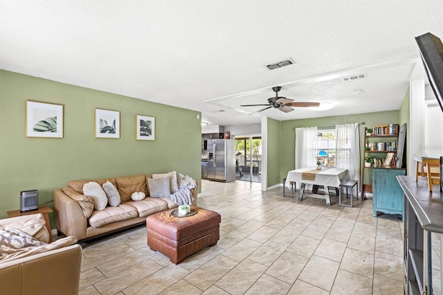 living room featuring ceiling fan and a textured ceiling