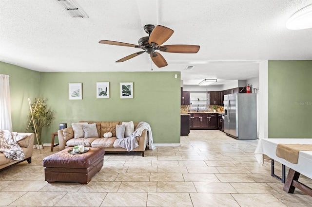 tiled living room with ceiling fan and a textured ceiling