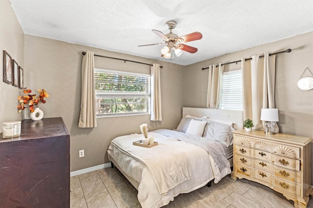 bedroom with ceiling fan, light tile patterned floors, and a textured ceiling