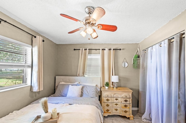 tiled bedroom featuring ceiling fan, a textured ceiling, and multiple windows