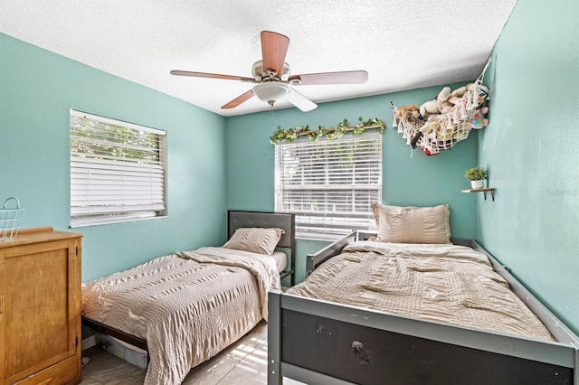 bedroom with ceiling fan, a textured ceiling, and multiple windows