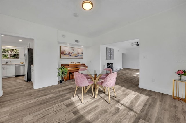 dining area with sink, light hardwood / wood-style floors, and ceiling fan