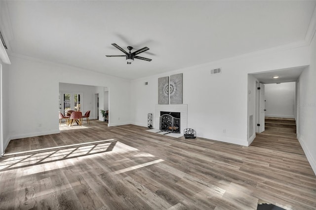 unfurnished living room featuring light hardwood / wood-style flooring, a fireplace, ornamental molding, and ceiling fan