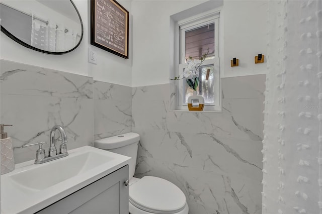 bathroom with tile walls, vanity, and toilet