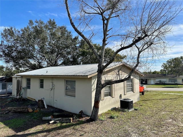 view of side of property featuring a lawn and central AC