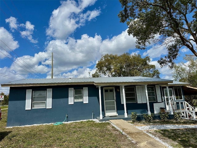 ranch-style home with stucco siding, metal roof, and a front yard