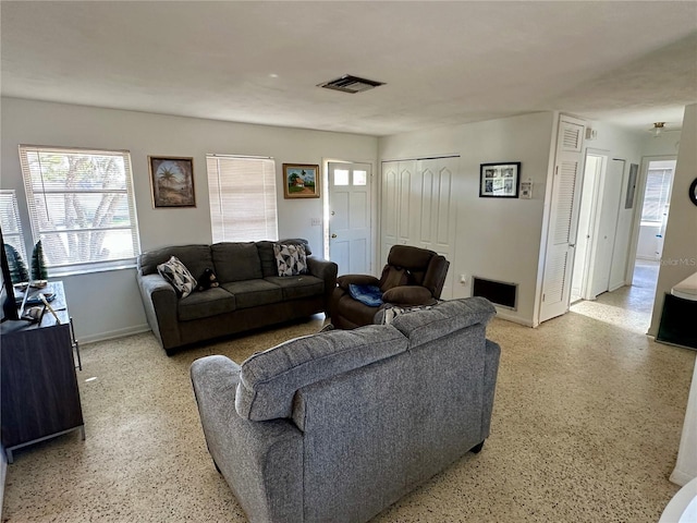 living room with light speckled floor, visible vents, and baseboards