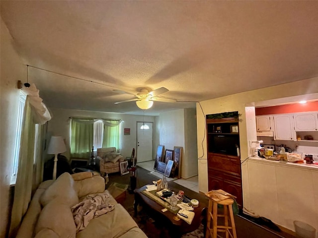 living room featuring ceiling fan and a textured ceiling